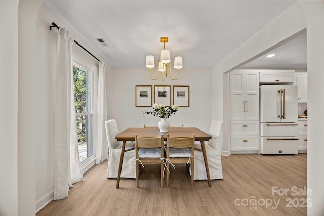 dining area with baseboards, light wood finished floors, visible vents, and a notable chandelier