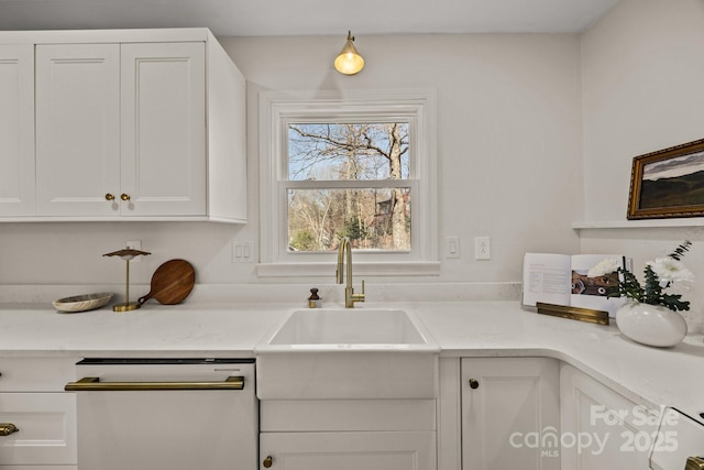 kitchen with white dishwasher, white cabinetry, and light countertops