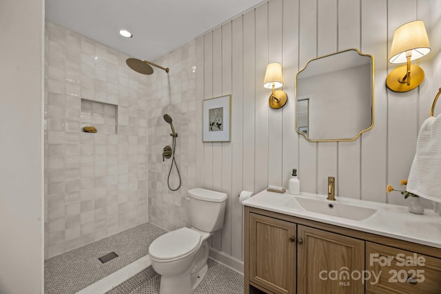 bathroom featuring a tile shower, vanity, and toilet