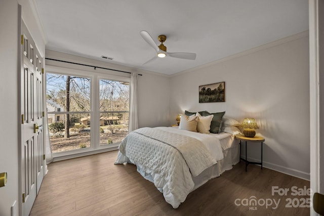 bedroom with ornamental molding, wood finished floors, visible vents, and baseboards