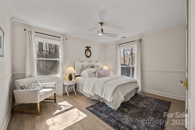 bedroom with a ceiling fan, crown molding, baseboards, and wood finished floors