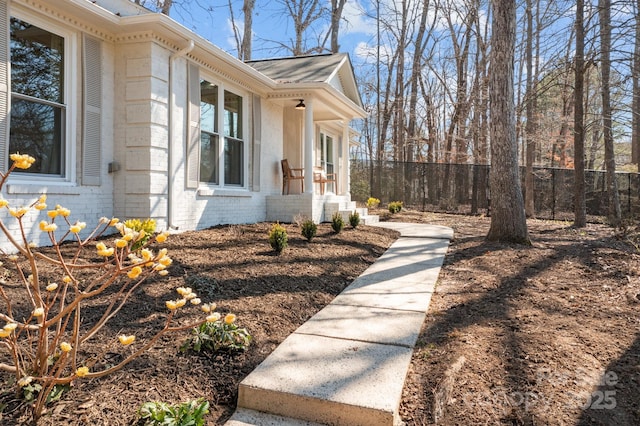 view of side of home featuring fence and brick siding