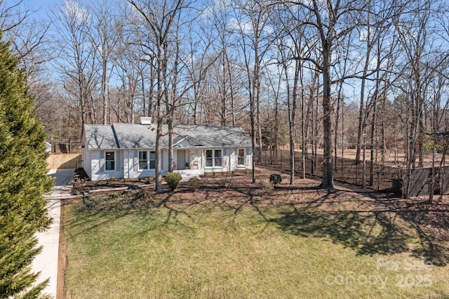 view of front of home with a chimney, fence, and a front yard