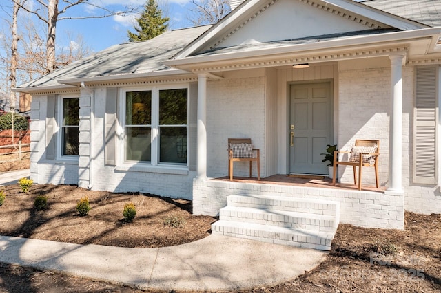 entrance to property with a porch and brick siding