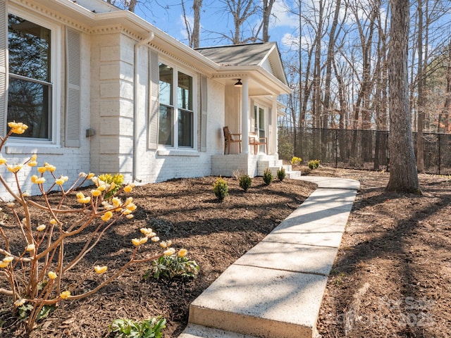 view of side of home with brick siding and fence