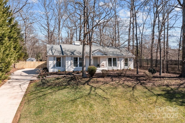 view of front of home featuring a chimney, fence, concrete driveway, and a front yard