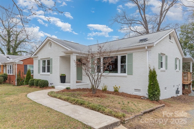 single story home with a shingled roof, a front yard, crawl space, and brick siding