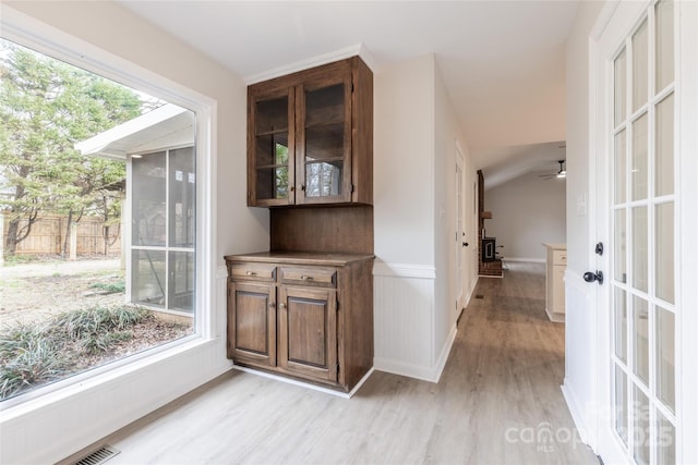 interior space with lofted ceiling, ceiling fan, light wood-type flooring, and visible vents