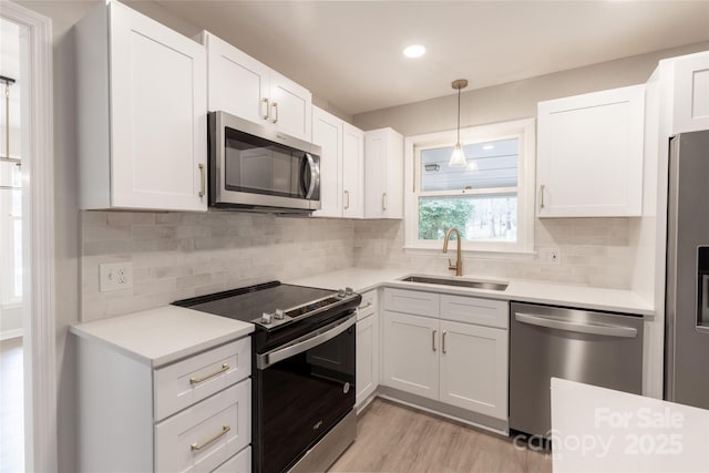 kitchen featuring light countertops, light wood-type flooring, appliances with stainless steel finishes, and a sink