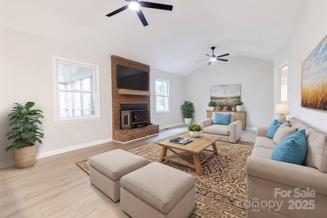 living area with a wood stove, wood finished floors, and ceiling fan