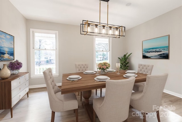dining room with light wood-type flooring, baseboards, and a notable chandelier