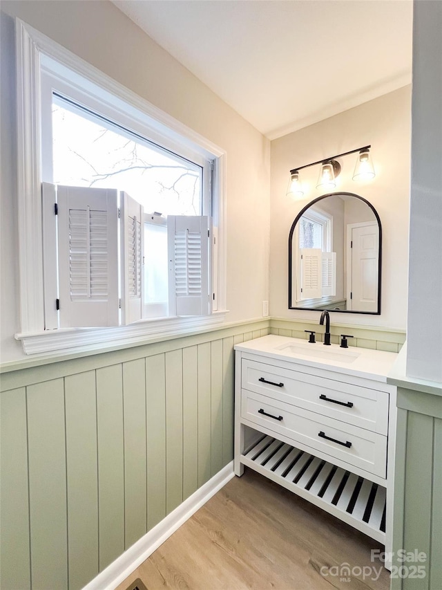 bathroom with a wainscoted wall, wood finished floors, and vanity