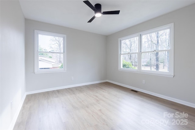 empty room with baseboards, a ceiling fan, wood finished floors, and visible vents