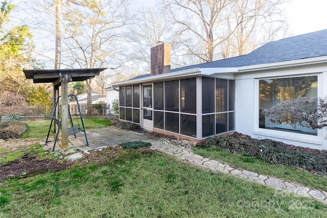 rear view of property with a chimney, a sunroom, fence, and a yard