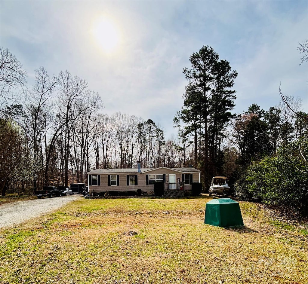 manufactured / mobile home with driveway, a chimney, and a front yard