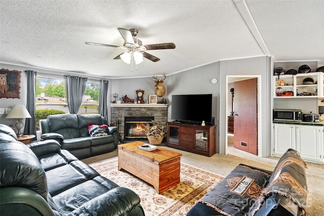 living area with a stone fireplace, a textured ceiling, ceiling fan, and light carpet
