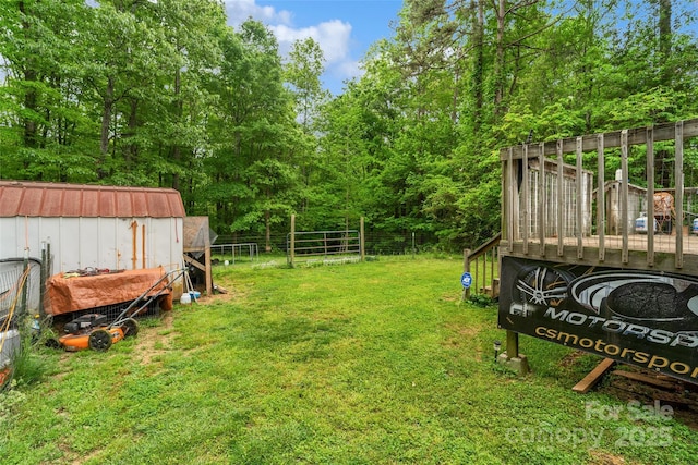 view of yard featuring fence, an outbuilding, and a deck