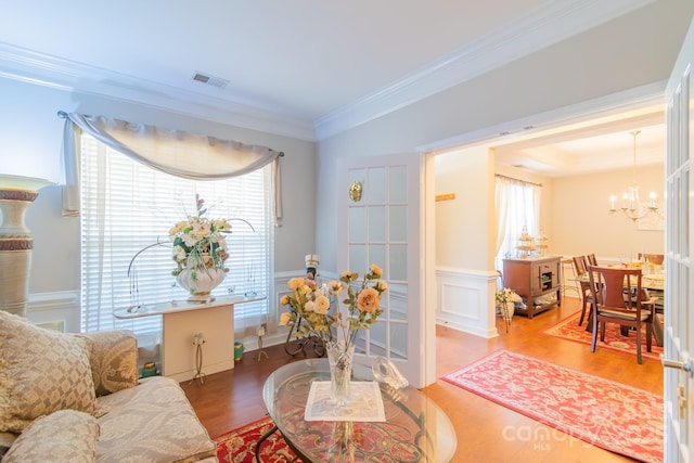 living area with visible vents, a healthy amount of sunlight, wainscoting, and crown molding