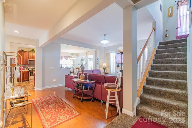 living area with baseboards, stairs, and light wood-style floors