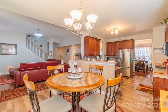 dining space featuring stairs, light wood-style floors, baseboards, and a chandelier