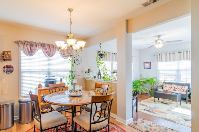 dining room featuring ceiling fan with notable chandelier, a healthy amount of sunlight, visible vents, and light wood-type flooring