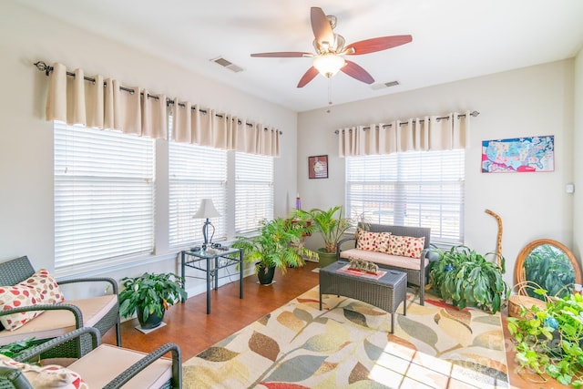 living area with visible vents, a ceiling fan, and wood finished floors