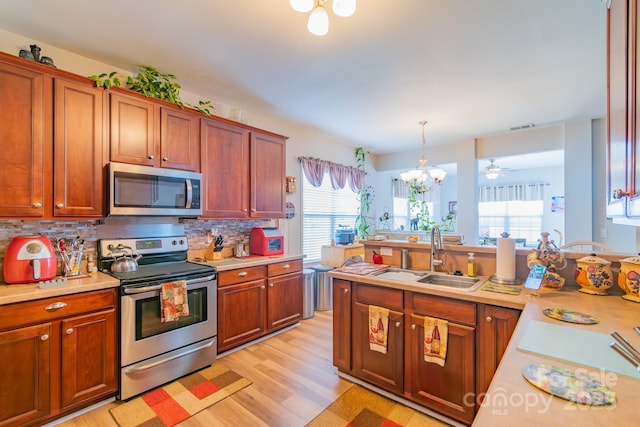 kitchen with light wood-type flooring, a sink, stainless steel appliances, light countertops, and decorative backsplash