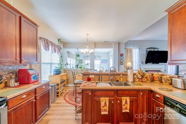 kitchen featuring dishwasher, light countertops, decorative backsplash, and a sink