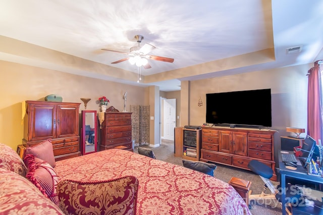 carpeted bedroom featuring visible vents, a ceiling fan, and a tray ceiling