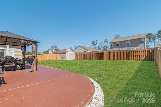 view of yard featuring an outbuilding, a fenced backyard, a gazebo, a storage shed, and a patio area