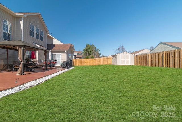 view of yard with a patio, a fenced backyard, a gazebo, an outdoor structure, and a storage shed