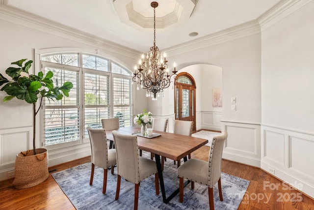 dining space with a wealth of natural light, a decorative wall, arched walkways, and wood finished floors