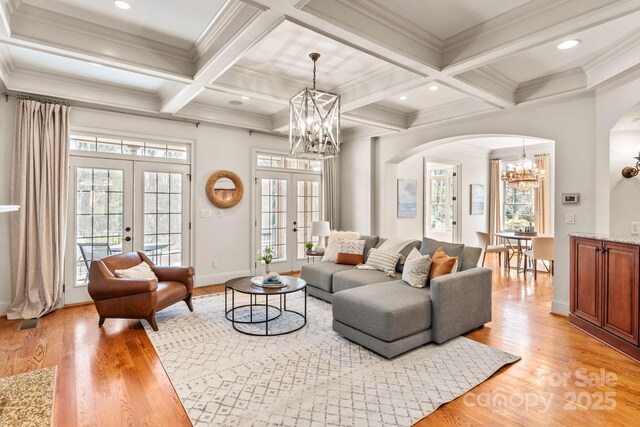 living room featuring a chandelier, french doors, beamed ceiling, and light wood-type flooring