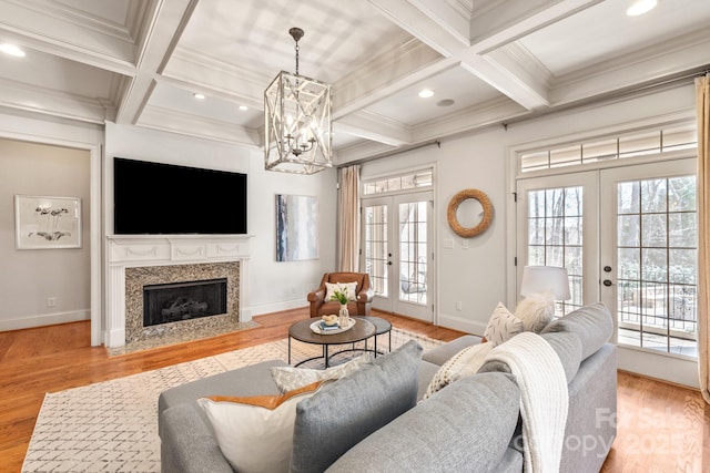 living area with coffered ceiling, a high end fireplace, french doors, light wood-type flooring, and beamed ceiling