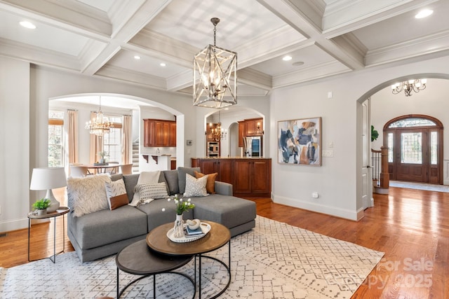 living room featuring arched walkways, light wood-style floors, a wealth of natural light, and a notable chandelier