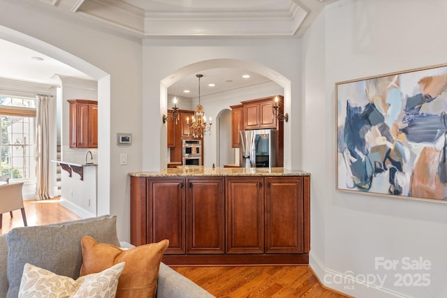 bar featuring a chandelier, appliances with stainless steel finishes, light wood-type flooring, and crown molding