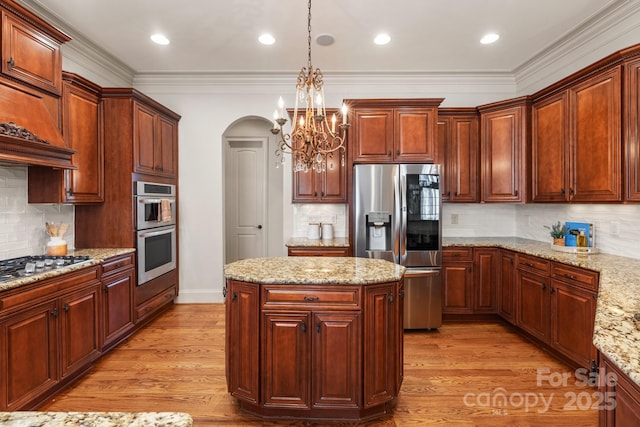 kitchen featuring arched walkways, stainless steel appliances, hanging light fixtures, light wood-type flooring, and a center island