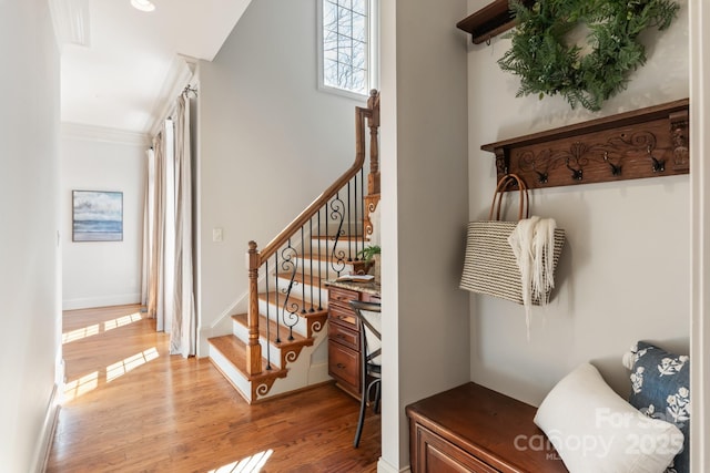 staircase featuring crown molding, baseboards, and wood finished floors