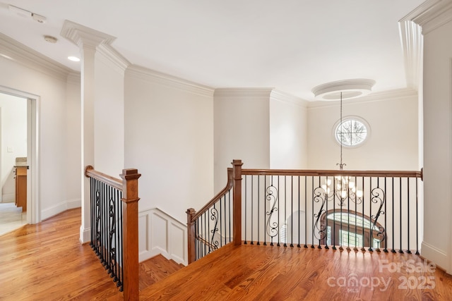 hall featuring crown molding, a notable chandelier, an upstairs landing, and wood finished floors