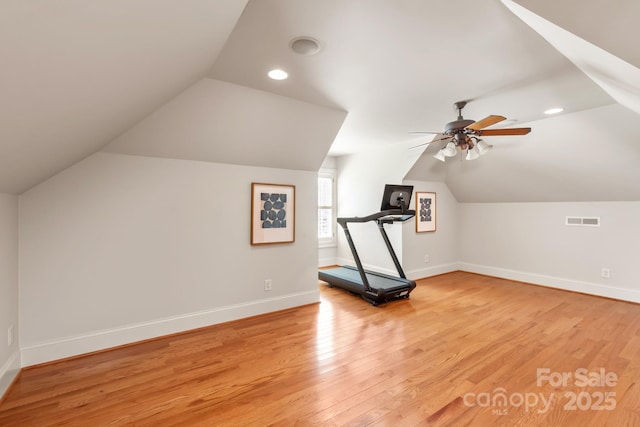 workout room featuring lofted ceiling, visible vents, light wood-style flooring, a ceiling fan, and baseboards