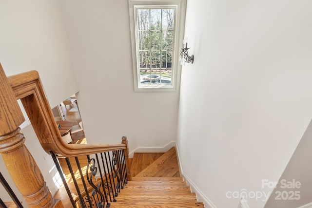 stairs with a wealth of natural light, baseboards, and wood finished floors