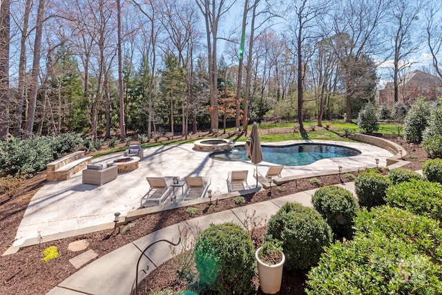 view of swimming pool featuring a patio area, a pool with connected hot tub, and a fire pit