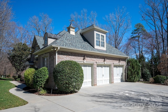 view of side of property featuring brick siding, driveway, and an attached garage