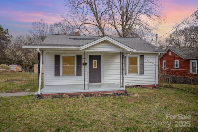 bungalow-style house featuring roof with shingles, a chimney, a porch, and a front yard