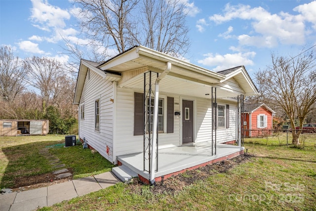 bungalow-style home with fence, a porch, cooling unit, and a front yard