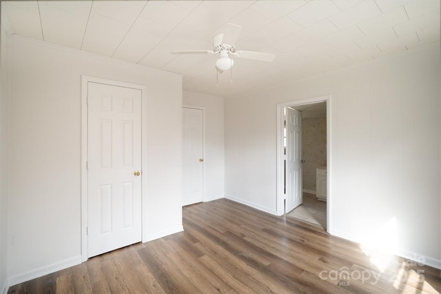 unfurnished bedroom featuring ceiling fan, crown molding, wood finished floors, and baseboards