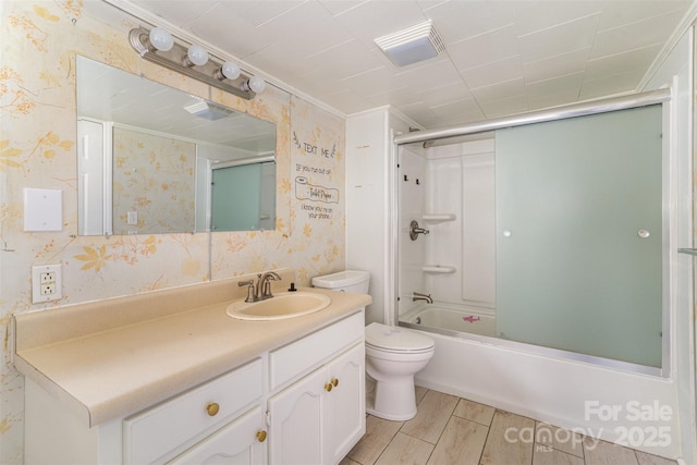 bathroom featuring toilet, wallpapered walls, enclosed tub / shower combo, and vanity