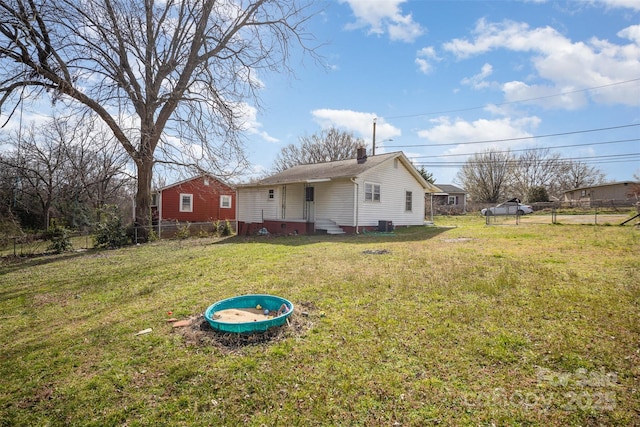 rear view of property featuring a chimney, fence, and a lawn