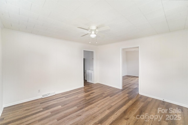 spare room featuring crown molding, visible vents, ceiling fan, wood finished floors, and baseboards