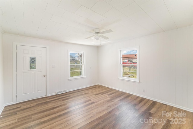 empty room featuring baseboards, ceiling fan, visible vents, and wood finished floors